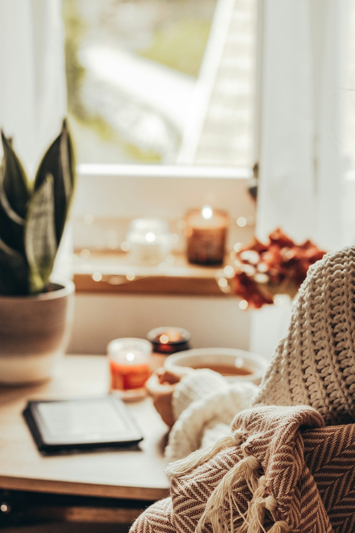 Femme en pull en maille tenant une tasse de thé près de bougies, ambiance cocooning du dimanche Image