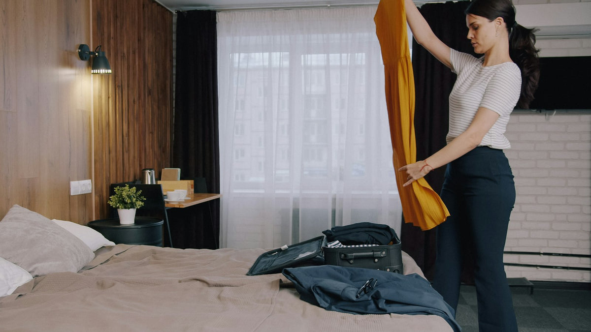 Femme préparant sa valise sur un lit dans une chambre d'hôtel avant un voyage Image