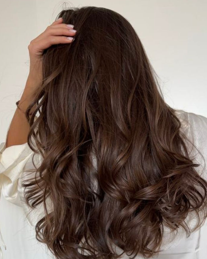 Long, volumineux cheveux ondulés brun foncé vus de dos, main sur la nuque. Nourishing Mask for Dry & Damaged Hair. Image