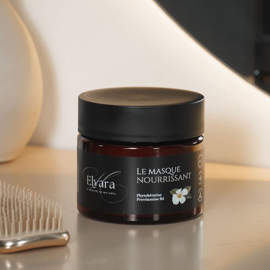 Pot de masque nourrissant pour cheveux secs et abîmés (Nourishing Mask) sur fond clair, avec pinceau à cheveux à gauche.